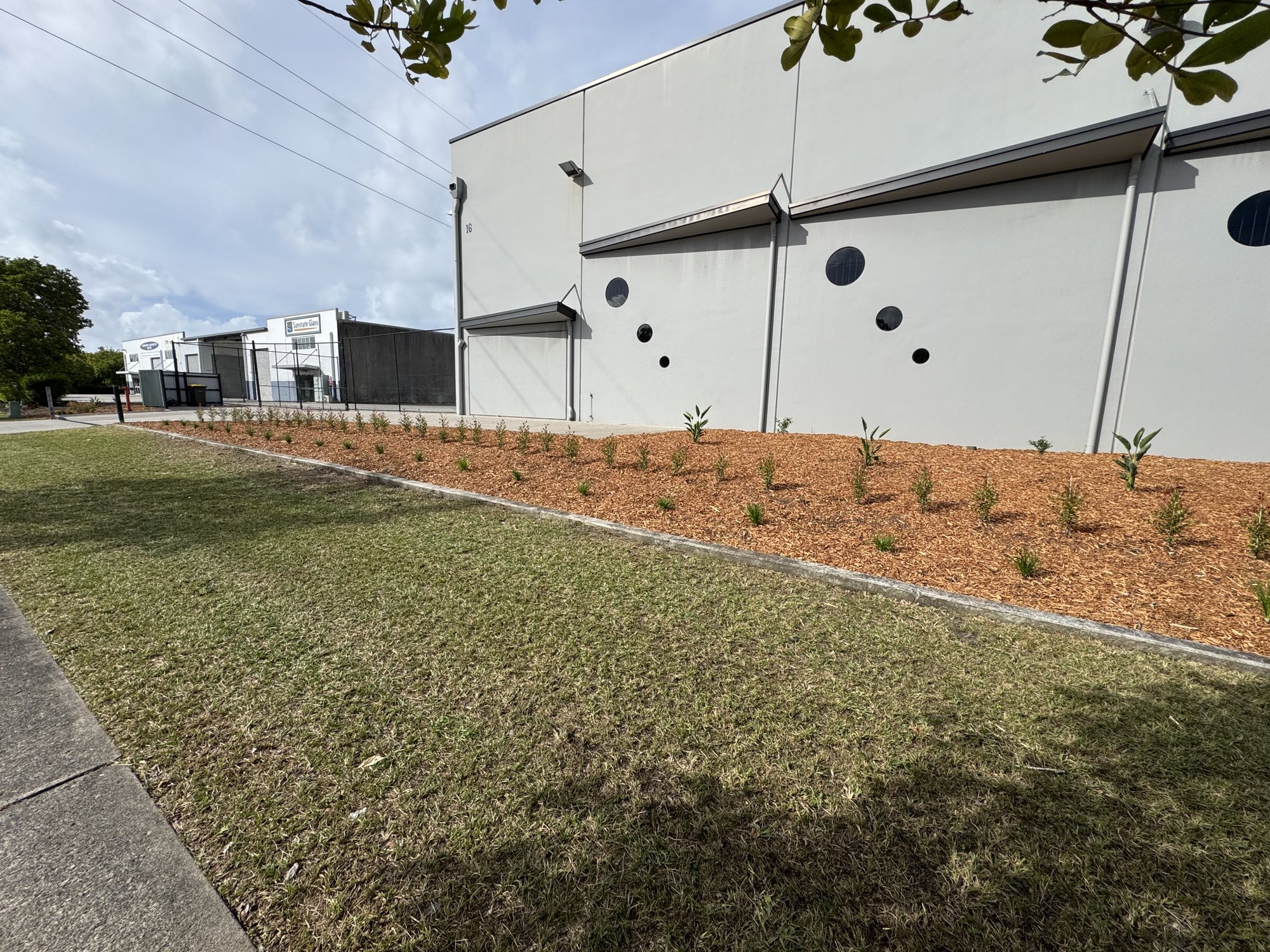 New mulched native garden bed along the same industrial unit wall